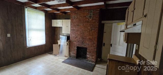 unfurnished living room featuring wood walls, a fireplace, and beamed ceiling