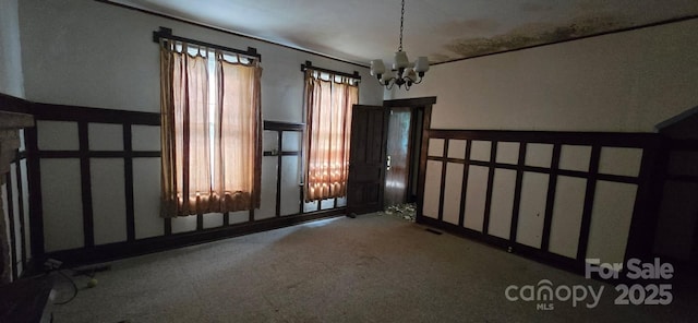 empty room with an inviting chandelier and carpet flooring