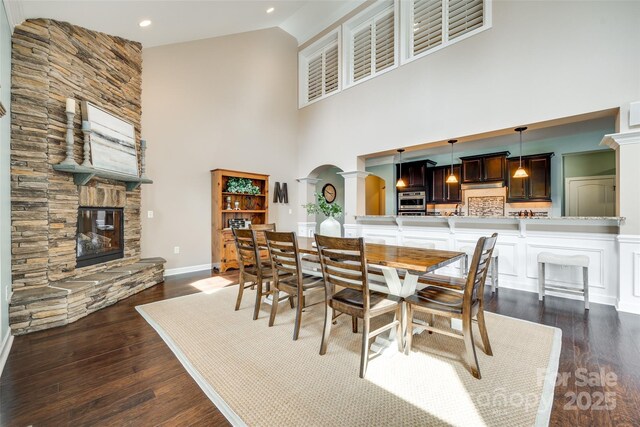 308 Hollister Estates Dr, Waxhaw, NC 28173 - dining space featuring a towering ceiling, a fireplace, dark wood-style floors, arched walkways, and recessed lighting