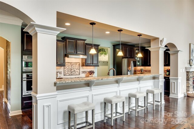 308 Hollister Estates Dr, Waxhaw, NC 28173 - kitchen featuring stainless steel appliances, arched walkways, tasteful backsplash, light stone counters, and recessed lighting