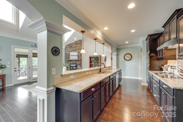 308 Hollister Estates Dr, Waxhaw, NC 28173 - kitchen featuring cooktop, a sink, under cabinet range hood, light stone counters, and dark wood-type flooring