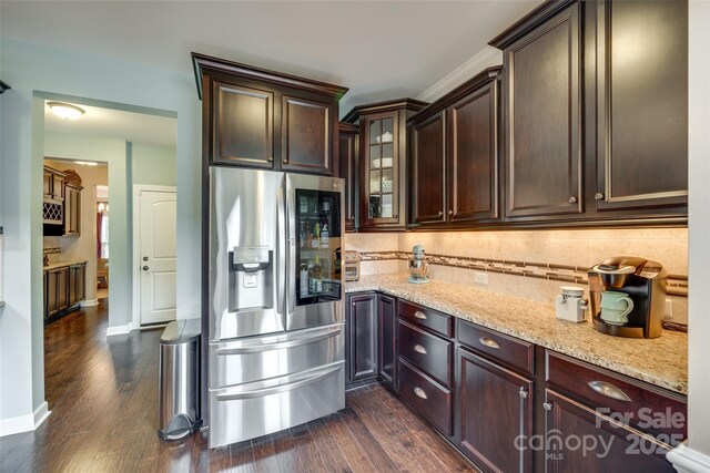 308 Hollister Estates Dr, Waxhaw, NC 28173 - kitchen featuring stainless steel refrigerator with ice dispenser, light stone counters, dark wood-type flooring, dark brown cabinets, and glass insert cabinets