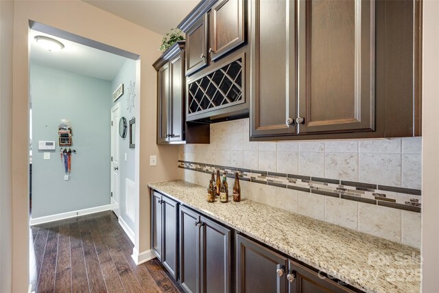 308 Hollister Estates Dr, Waxhaw, NC 28173 - kitchen featuring dark wood-type flooring, backsplash, light stone counters, dark brown cabinets, and baseboards
