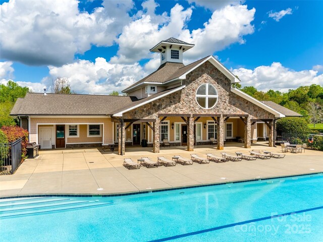 308 Hollister Estates Dr, Waxhaw, NC 28173 - back of property featuring a patio area, stone siding, a community pool, and a shingled roof