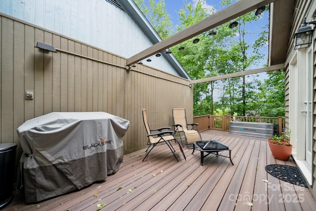 wooden deck with an outdoor fire pit and area for grilling