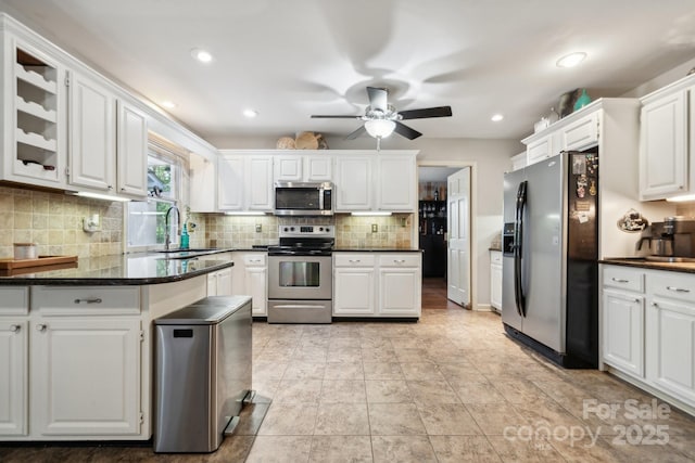 kitchen with a ceiling fan, white cabinetry, a sink, appliances with stainless steel finishes, and backsplash