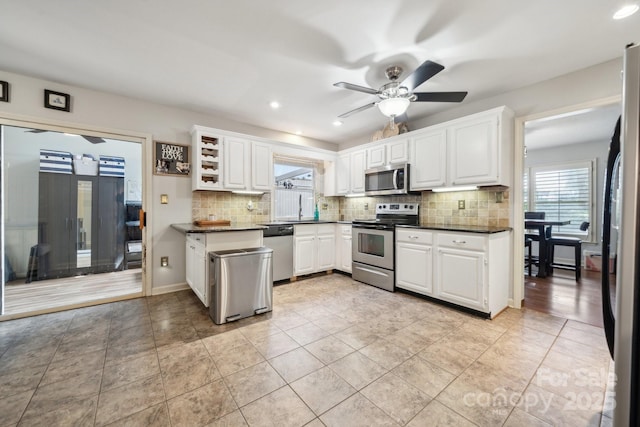 kitchen featuring dark countertops, appliances with stainless steel finishes, a wealth of natural light, and tasteful backsplash