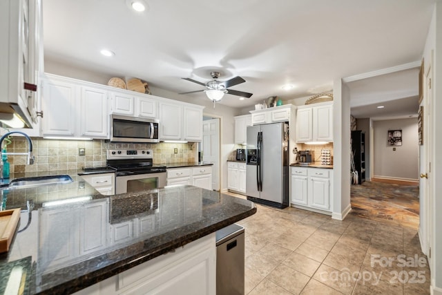 kitchen featuring decorative backsplash, ceiling fan, appliances with stainless steel finishes, a sink, and white cabinets
