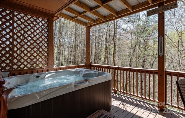 wooden deck featuring a view of trees and a hot tub