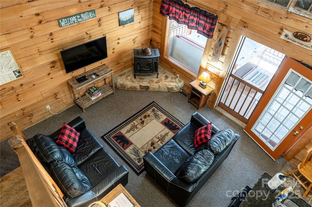 carpeted living room featuring a wood stove and wooden walls