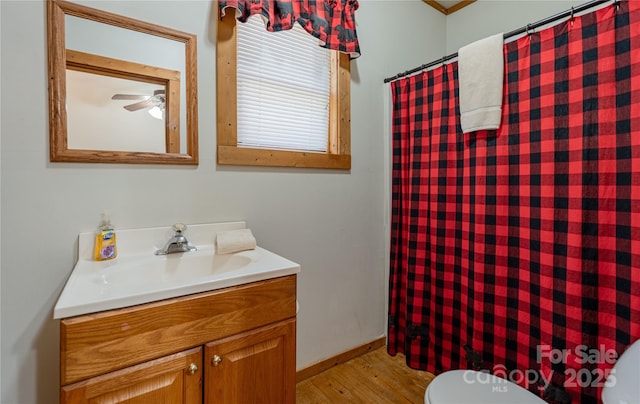 bathroom featuring toilet, a shower with curtain, wood finished floors, vanity, and ceiling fan