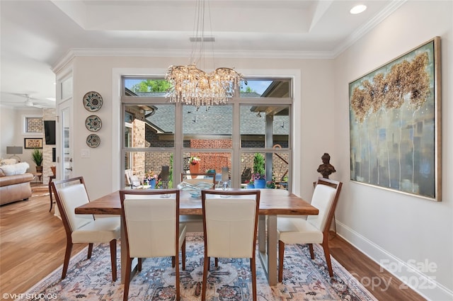 dining room featuring a raised ceiling, baseboards, wood finished floors, and a chandelier
