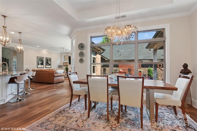dining room featuring crown molding, an inviting chandelier, wood finished floors, and visible vents