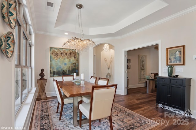 dining space featuring an inviting chandelier, a raised ceiling, arched walkways, visible vents, and dark wood-style floors