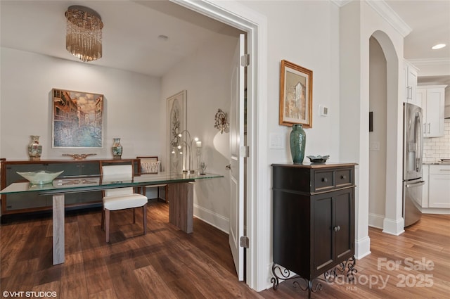 interior space featuring baseboards, arched walkways, crown molding, and wood finished floors