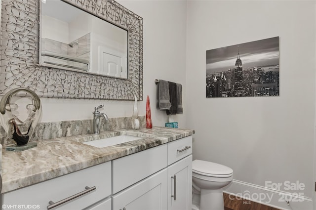 bathroom featuring toilet, wood finished floors, and vanity
