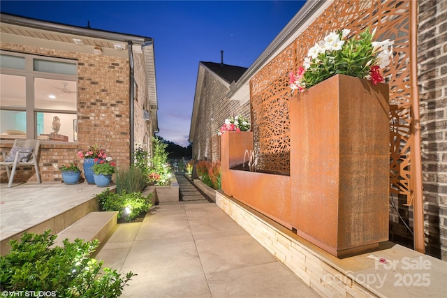 view of property exterior with brick siding and a patio