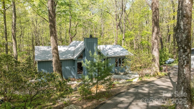 view of front of house featuring a wooded view and a chimney