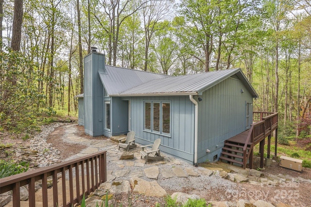 view of side of property featuring stairway, a deck, a chimney, and metal roof