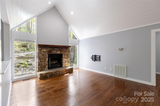 unfurnished living room with visible vents, high vaulted ceiling, wood finished floors, and a stone fireplace