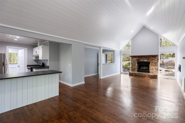 unfurnished living room featuring lofted ceiling, a fireplace, baseboards, dark wood-style floors, and wooden ceiling