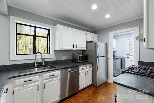 kitchen with wall chimney range hood, recessed lighting, washer and clothes dryer, a sink, and appliances with stainless steel finishes