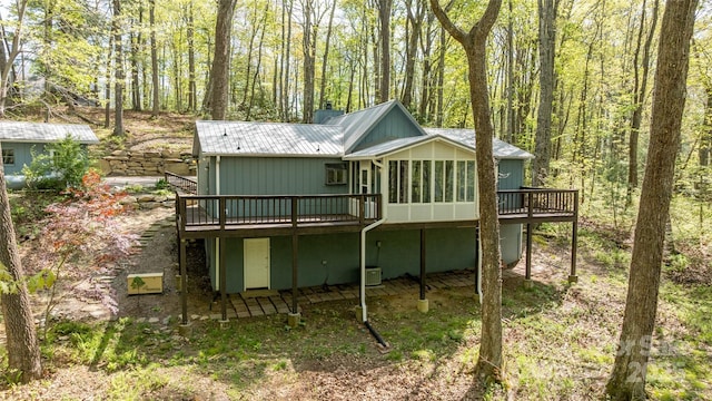 rear view of house featuring a wooden deck and metal roof