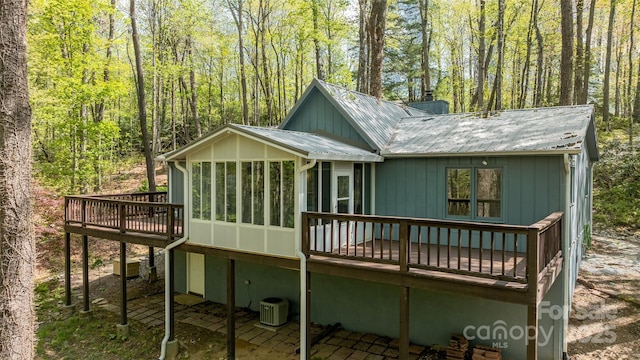 rear view of property featuring metal roof, a sunroom, central AC, and a deck