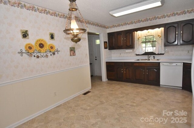 902 Church St NW, Valdese, NC 28690 - kitchen with wainscoting, dark brown cabinetry, white dishwasher, light countertops, and a sink