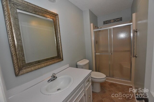 902 Church St NW, Valdese, NC 28690 - bathroom featuring tile patterned flooring, vanity, toilet, a textured ceiling, and a stall shower