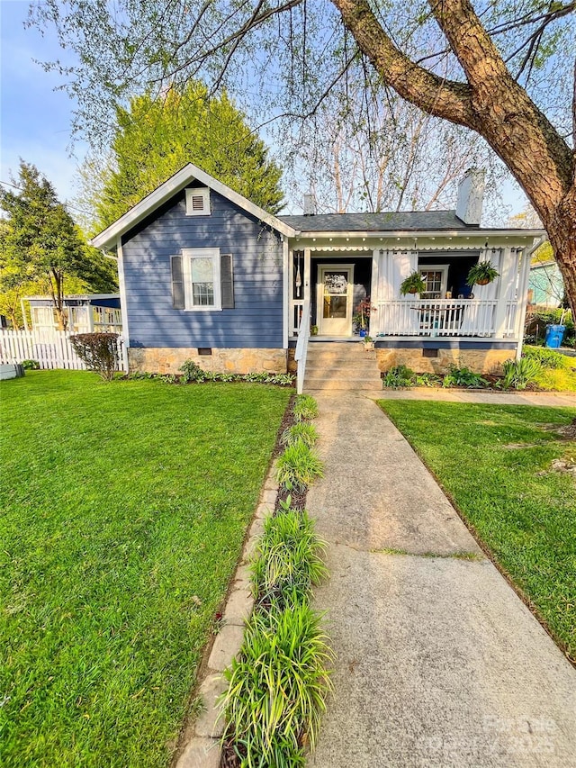 view of front of home featuring a chimney, a porch, a front lawn, and crawl space