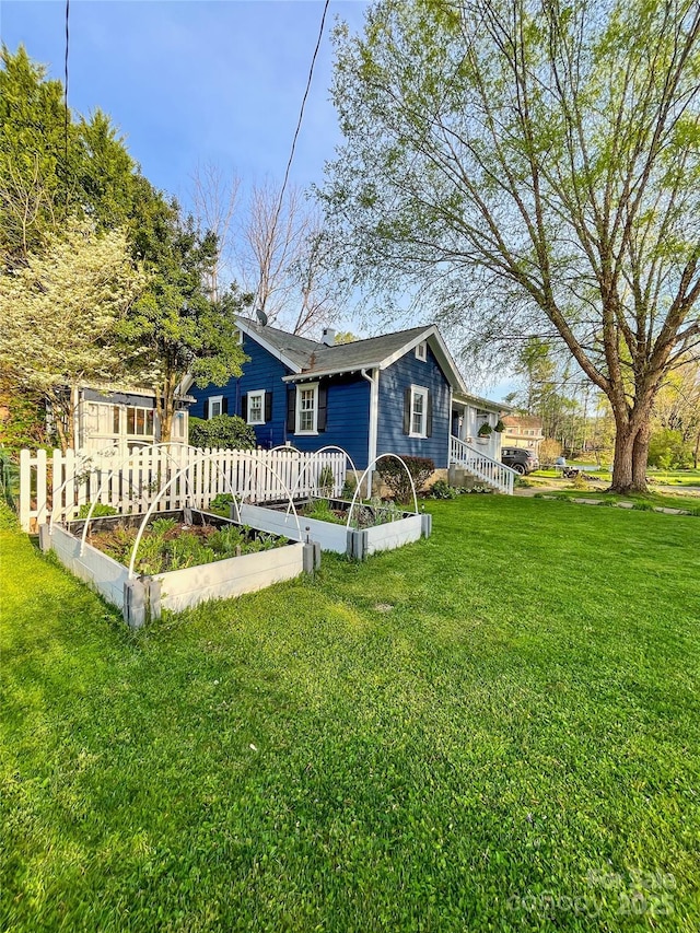 back of house featuring a yard and a vegetable garden
