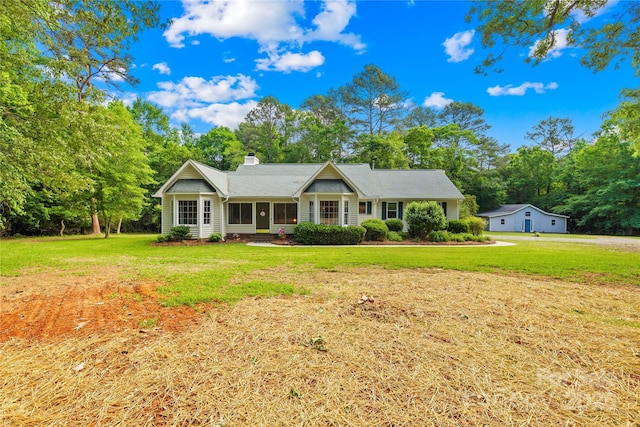 ranch-style house featuring a chimney, a front lawn, and view of wooded area