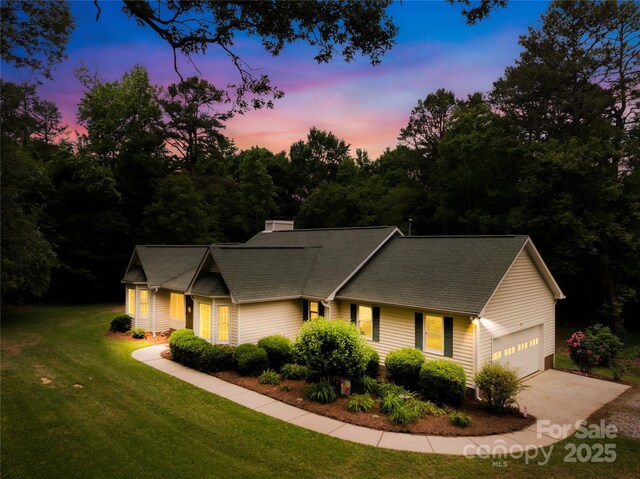 view of front facade featuring a garage, driveway, a front lawn, and roof with shingles