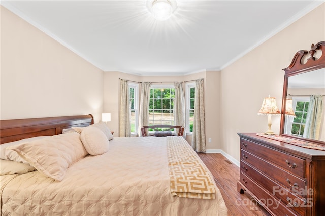 bedroom with wood finished floors, baseboards, and ornamental molding