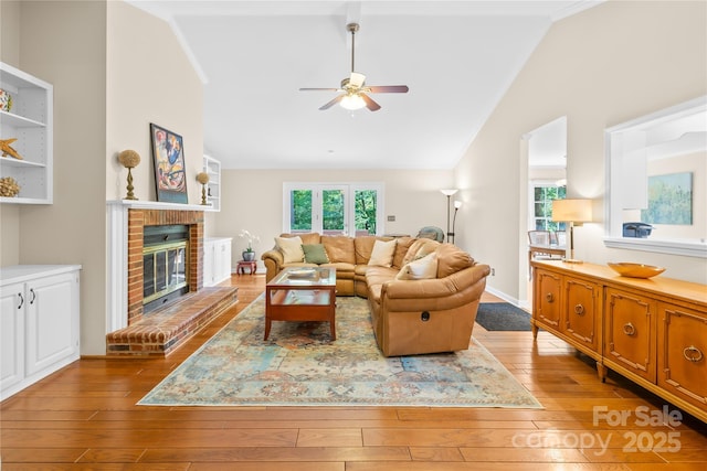 living room with a ceiling fan, hardwood / wood-style flooring, a fireplace, and high vaulted ceiling