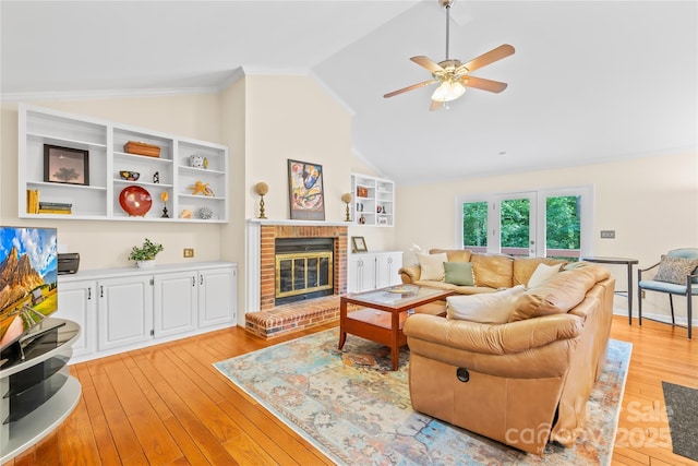 living area featuring lofted ceiling, a ceiling fan, light wood-style flooring, and a fireplace