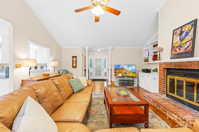 living room featuring vaulted ceiling, ornamental molding, a ceiling fan, wood finished floors, and a fireplace