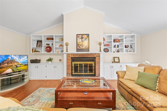 living area featuring vaulted ceiling, light wood finished floors, and a fireplace