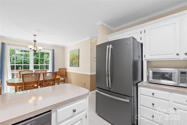 kitchen with appliances with stainless steel finishes, light countertops, a chandelier, white cabinets, and hanging light fixtures