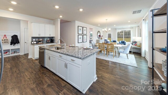 kitchen with light stone countertops, dishwasher, a sink, ornamental molding, and white cabinetry