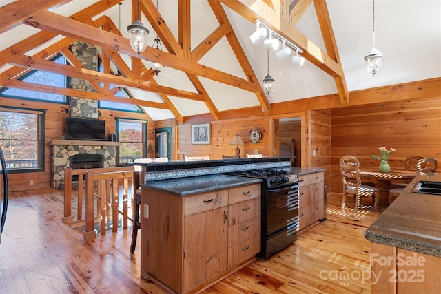 969 Twin Bridges Dr, Fleetwood, NC 28626 - kitchen with beamed ceiling, black gas stove, wood walls, and light wood-style floors