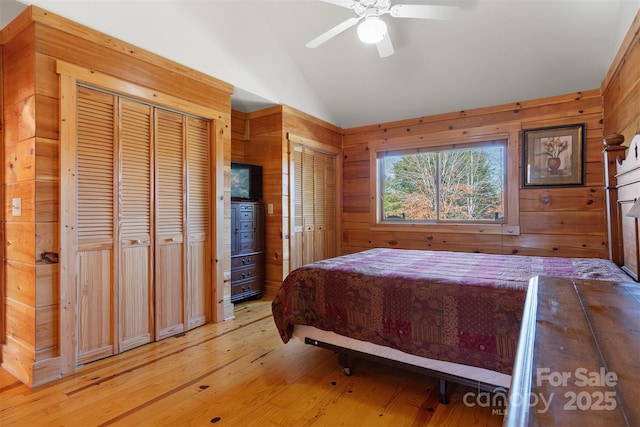 969 Twin Bridges Dr, Fleetwood, NC 28626 - bedroom featuring lofted ceiling, a ceiling fan, light wood-style flooring, wood walls, and two closets