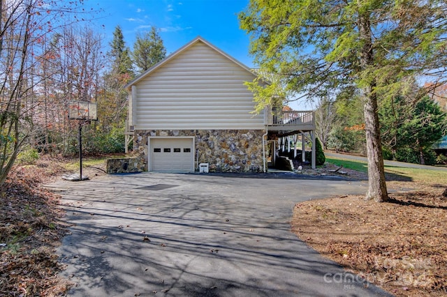 969 Twin Bridges Dr, Fleetwood, NC 28626 - view of home's exterior with a deck, an attached garage, stone siding, and driveway