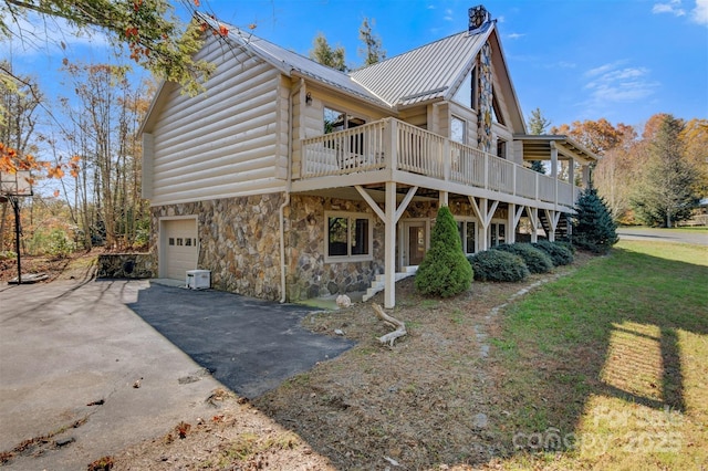 969 Twin Bridges Dr, Fleetwood, NC 28626 - view of property exterior with aphalt driveway, an attached garage, stone siding, metal roof, and a chimney