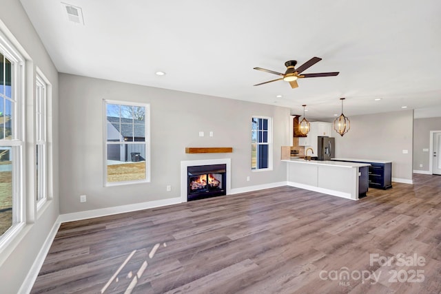 unfurnished living room with baseboards, plenty of natural light, and wood finished floors