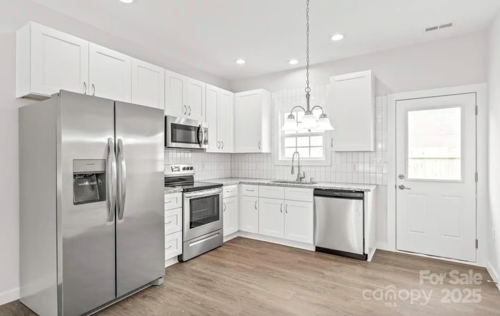 kitchen featuring appliances with stainless steel finishes, a sink, white cabinetry, recessed lighting, and visible vents