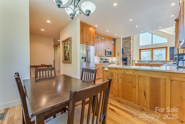 kitchen with recessed lighting, light wood-style floors, appliances with stainless steel finishes, and glass insert cabinets