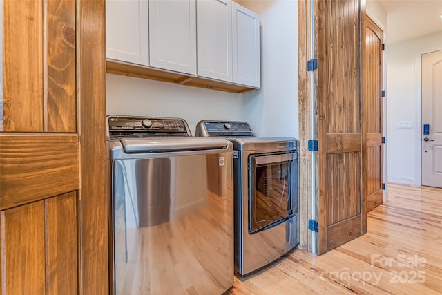 washroom with cabinet space, light wood finished floors, and washer and dryer