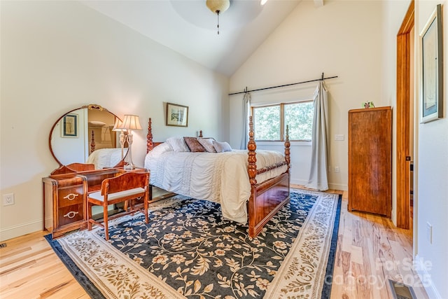 bedroom featuring a ceiling fan, baseboards, light wood finished floors, visible vents, and high vaulted ceiling